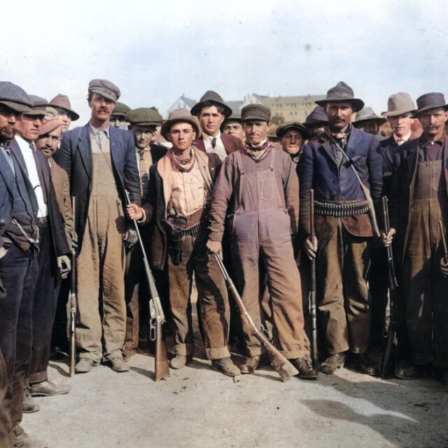 Miners from the 1913 Colorado Coalfield War, some armed, in a colorized photo.