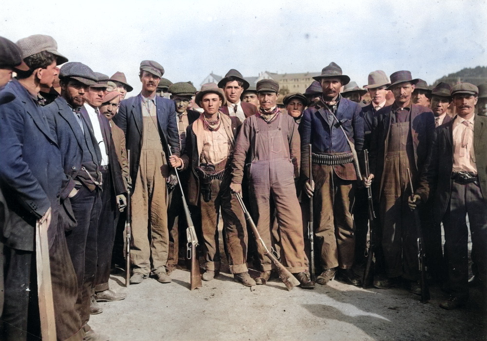 Miners from the 1913 Colorado Coalfield War, some armed, in a colorized photo.