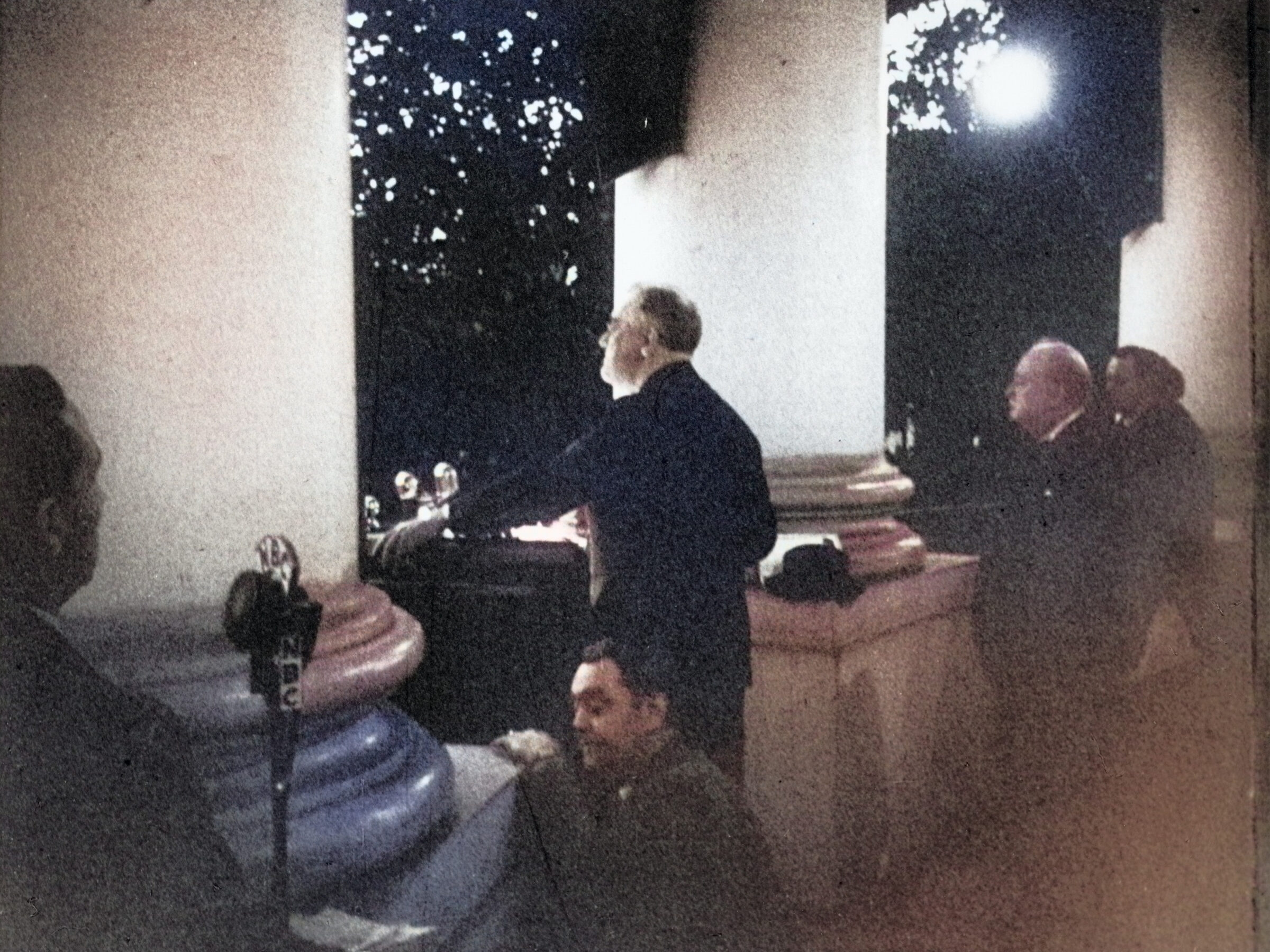 President Roosevelt and British Prime Minister Winston Churchill on Christmas Eve, 1941, standing at a White House podium weeks after the attack on Pearl Harbor, with an NBC microphone and a man in the foreground.