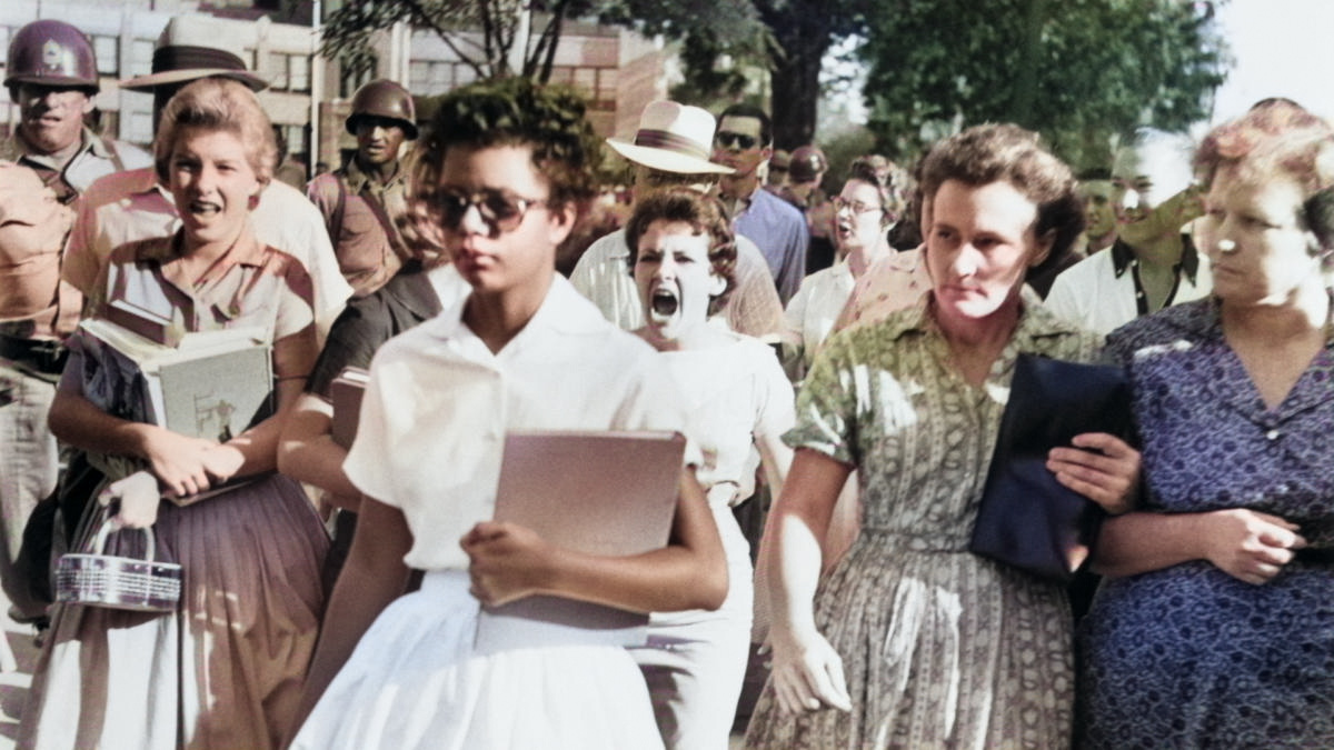 Colorized photo of Elizabeth Eckford, one of the Little Rock Nine, walking alone through a hostile mob during the desegregation of Central High School in 1957.