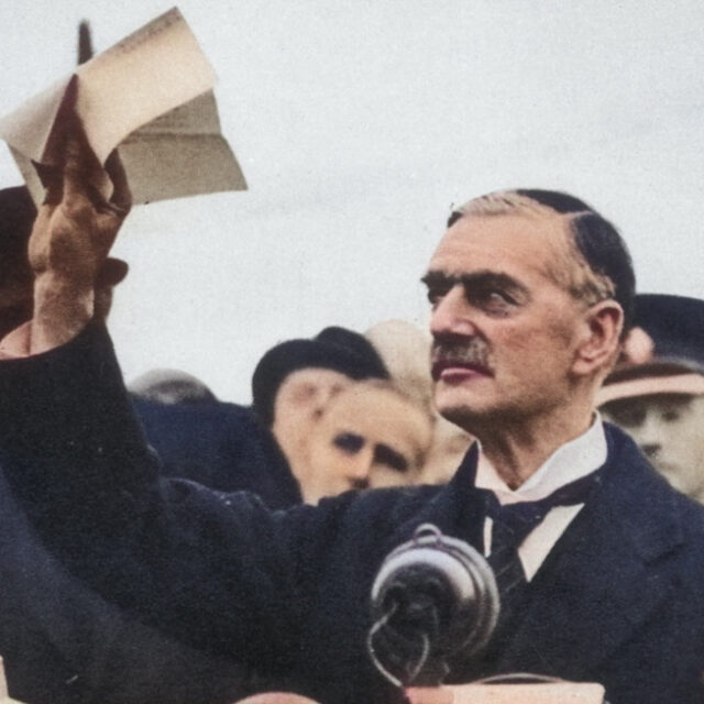 Neville Chamberlain, in a colorized photo, raising the Munich Agreement.