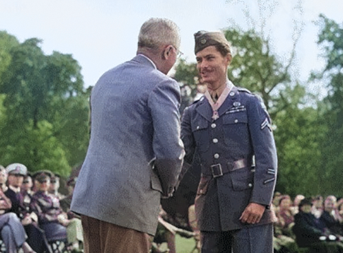 President Harry Truman, on the left, presenting the Medal of Honor to a uniformed Private Desmond Doss, on the right, amidst an audience in an outdoor setting.