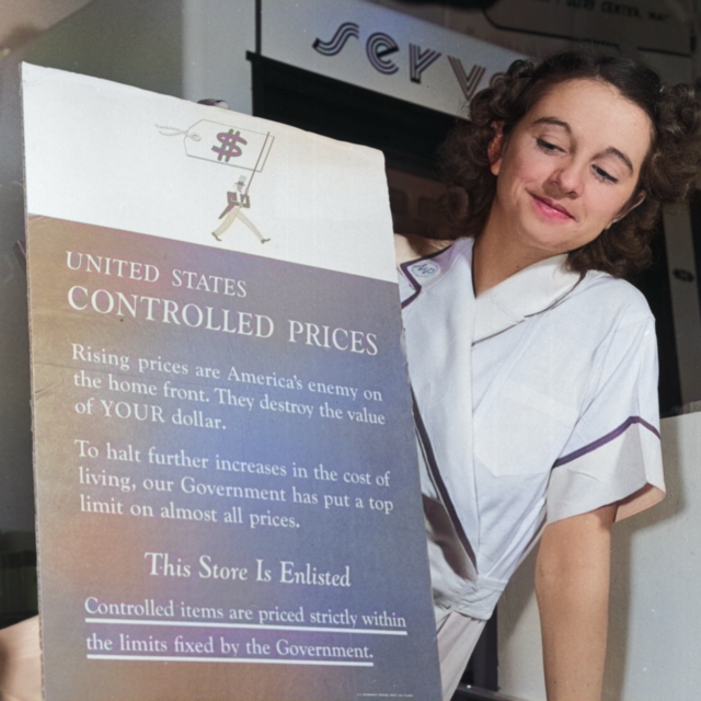 Young lady smiling at a sign in a storefront window that reads 'United States Controlled Prices... This store is enlisted'.
